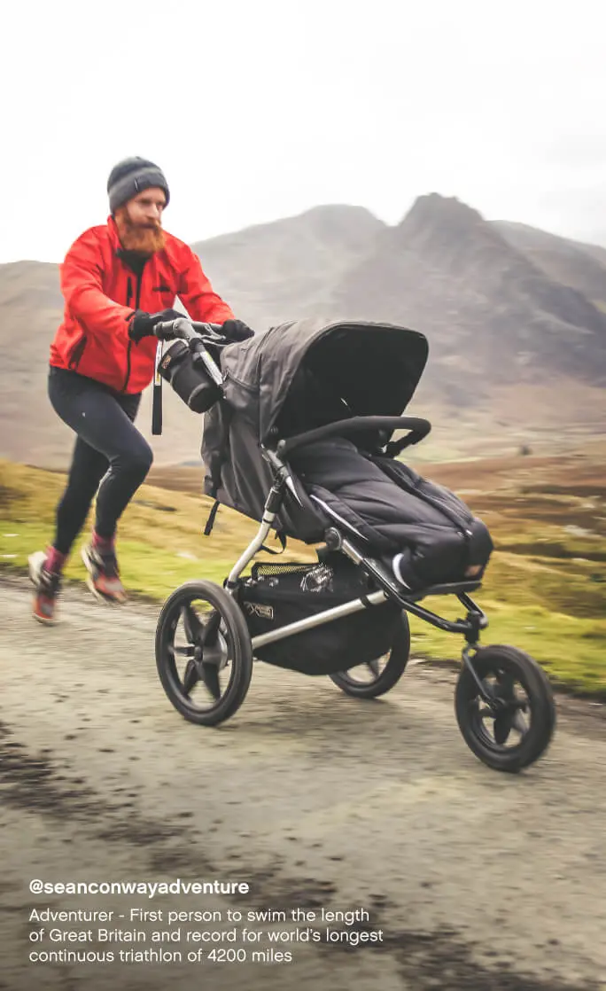 Mountain Buggy terrain all terrain 3-wheel pram with sleeping bag – dad running on a mountain trail